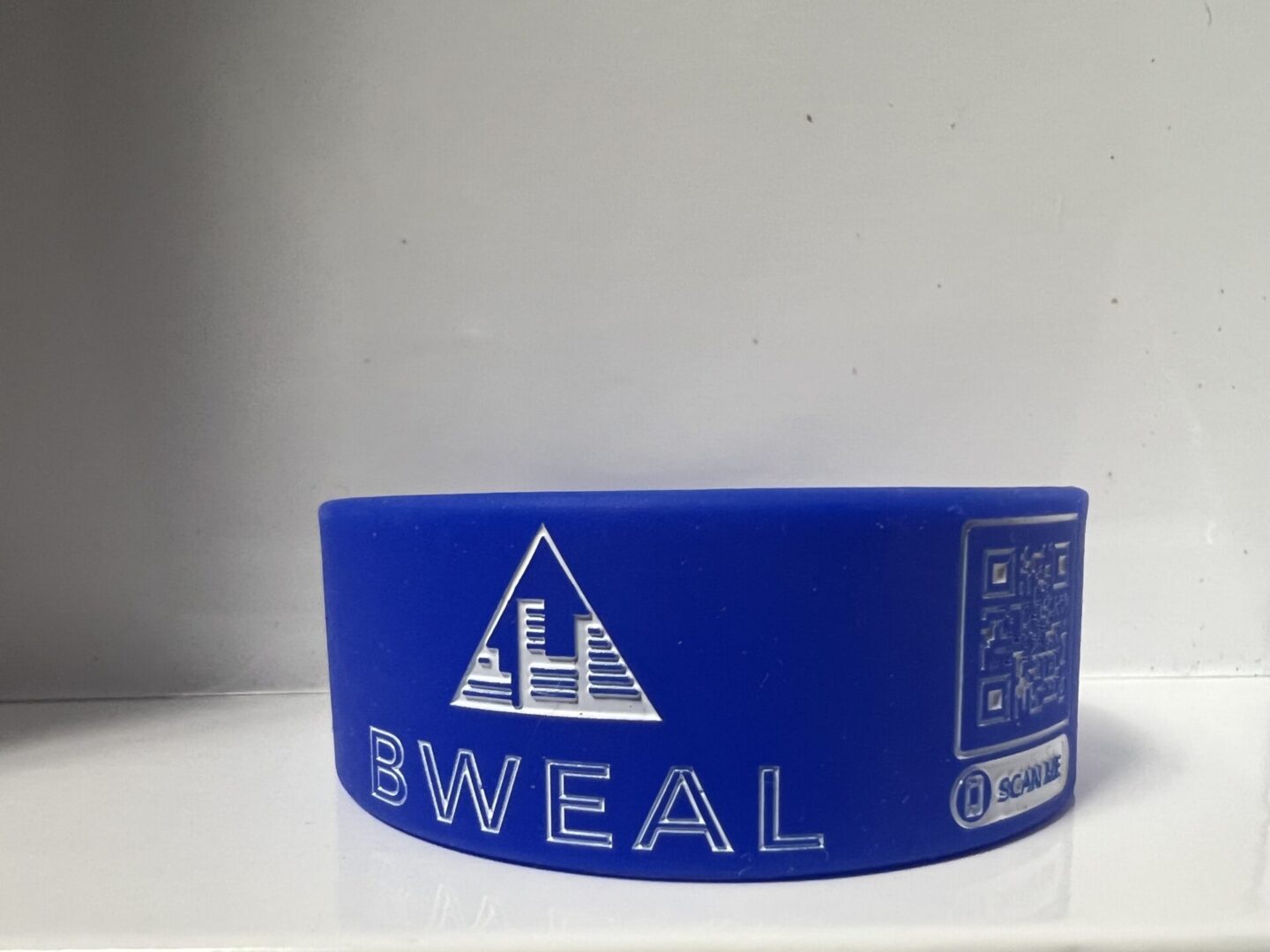 A blue wristband with the word " bweal " on it.