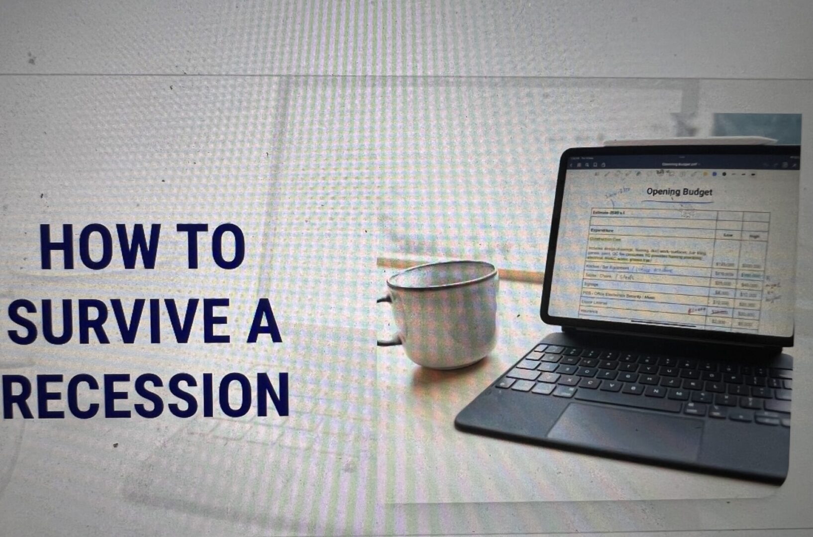 A laptop and cup on the table with text that reads " how to survive a recession ".